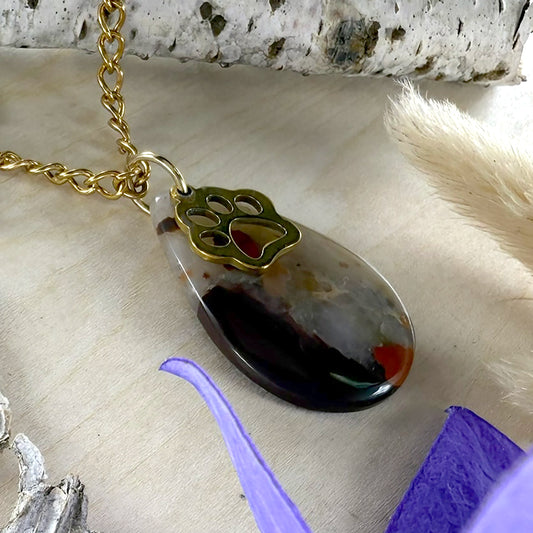Necklace with a paw-shaped pendant on a textured surface