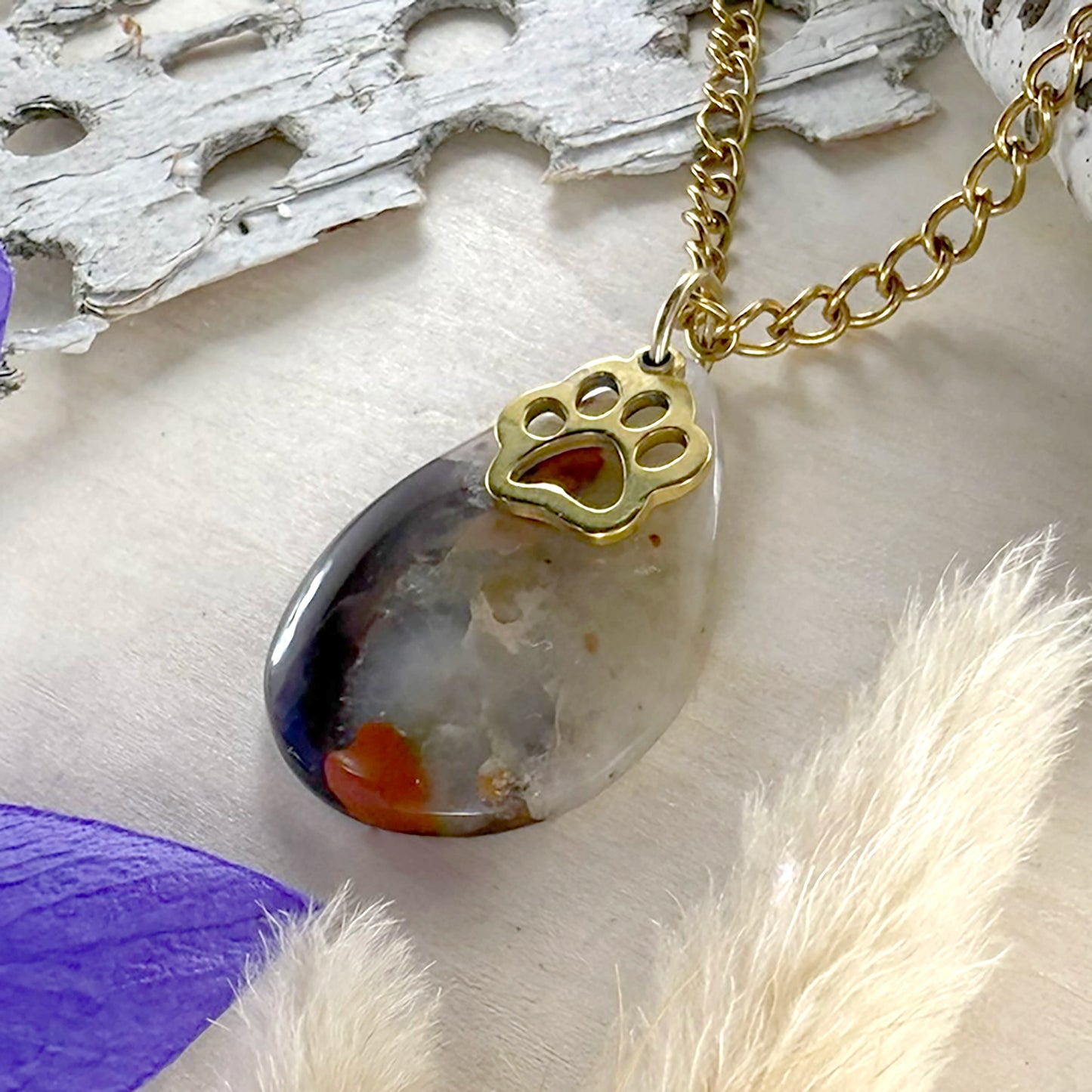 Necklace with a gold paw-shaped pendant on a wood surface