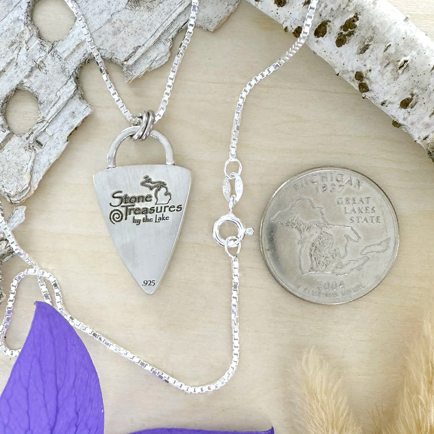 Silver necklace with a pendant on a natural wood surface