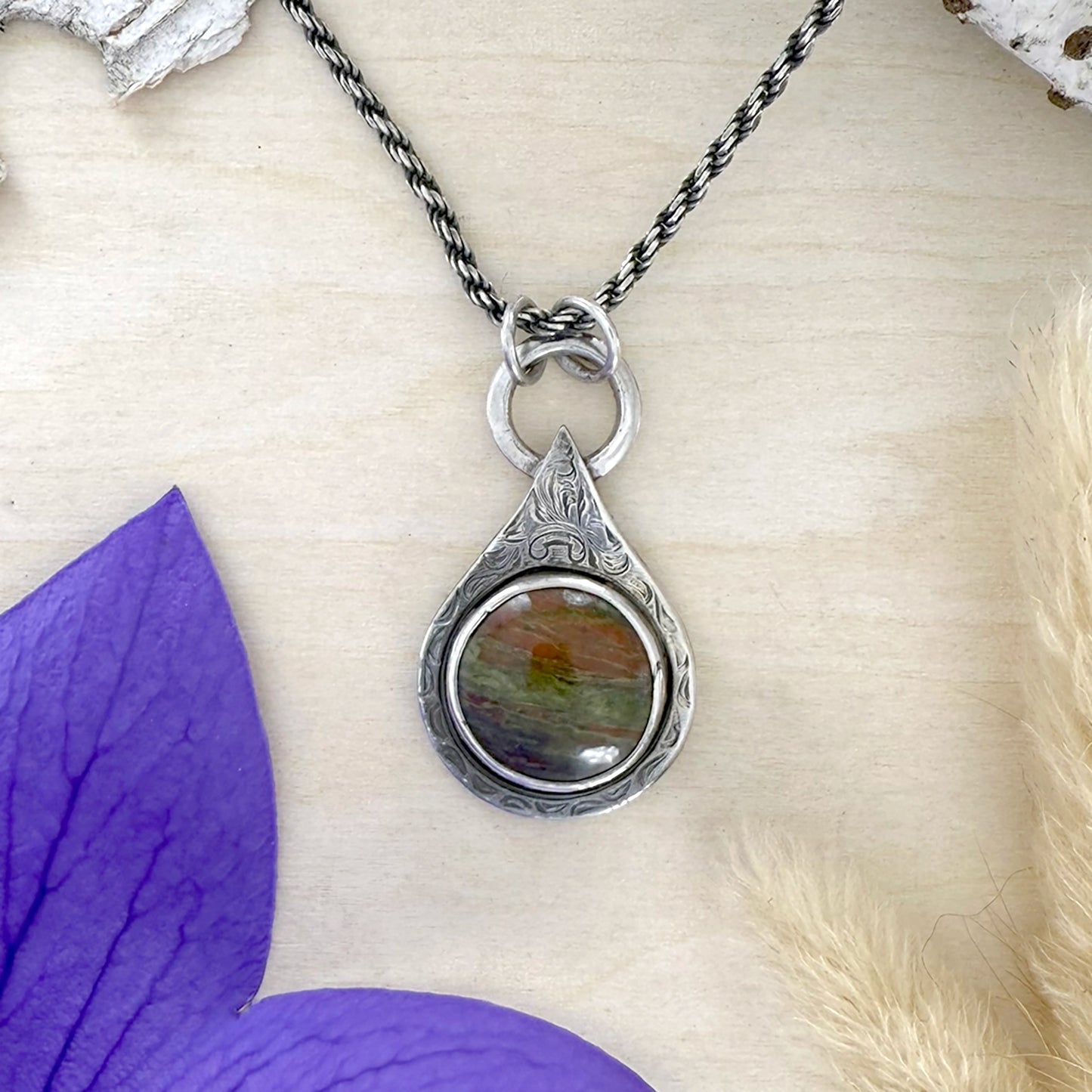 Silver pendant necklace with Lake Michigan Unakite on a wood surface with purple and beige elements