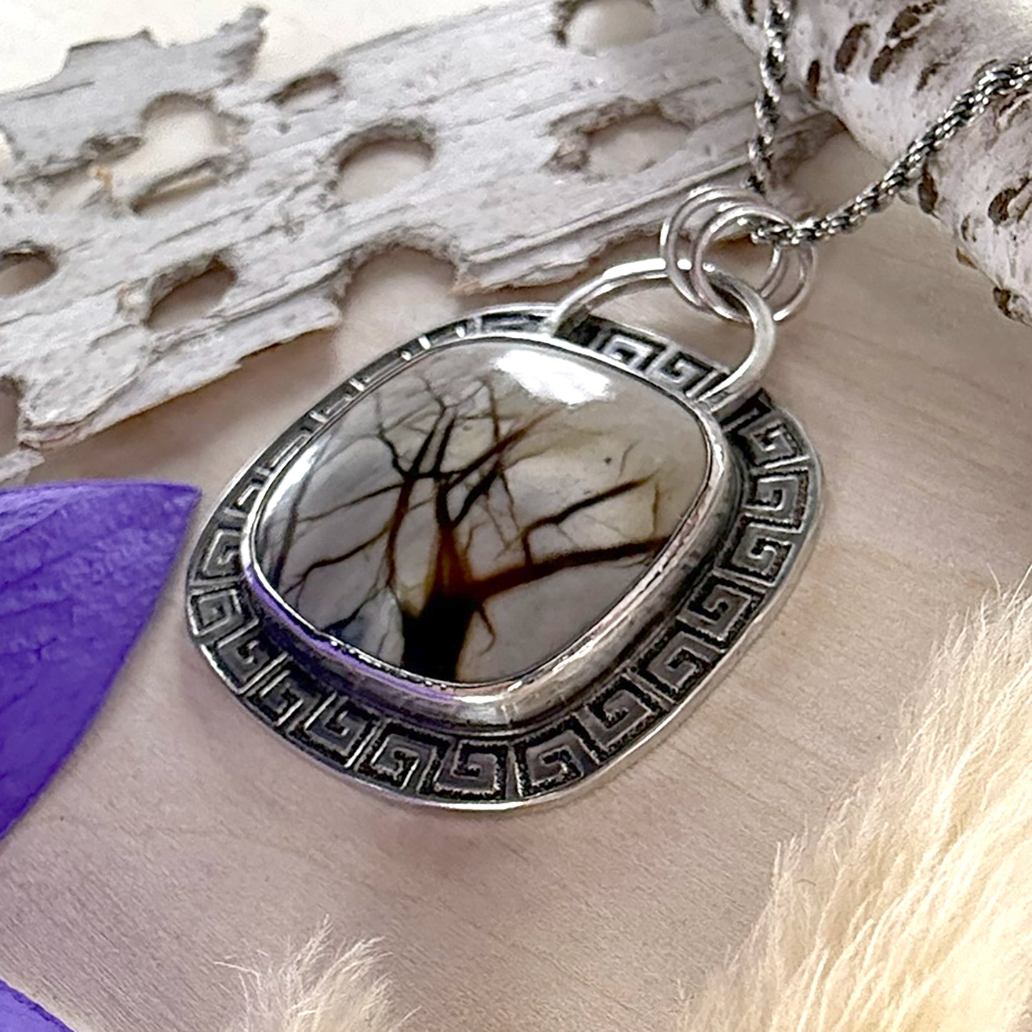 Silver pendant with tree design on a natural background