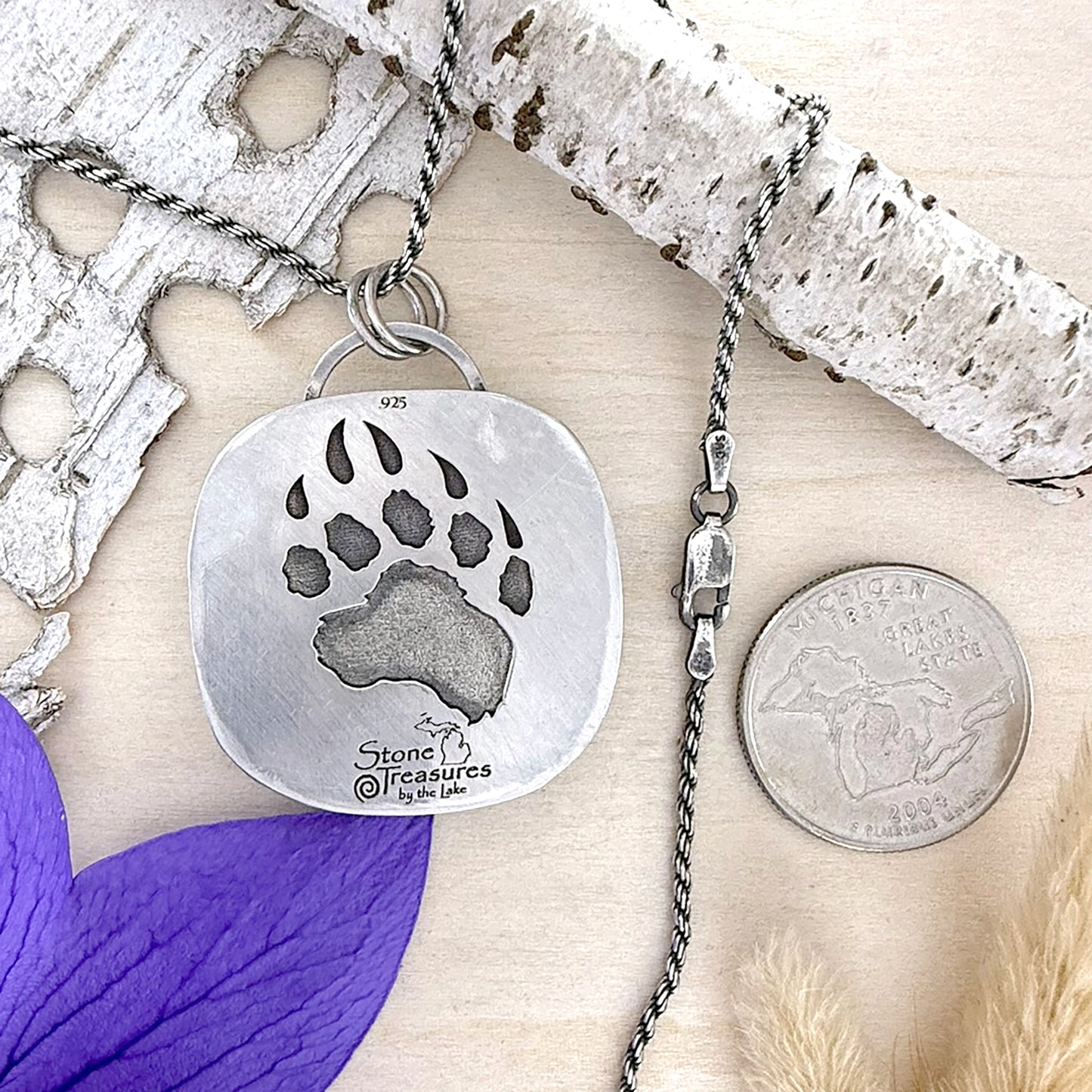 Silver pendant with paw print design on a wooden surface