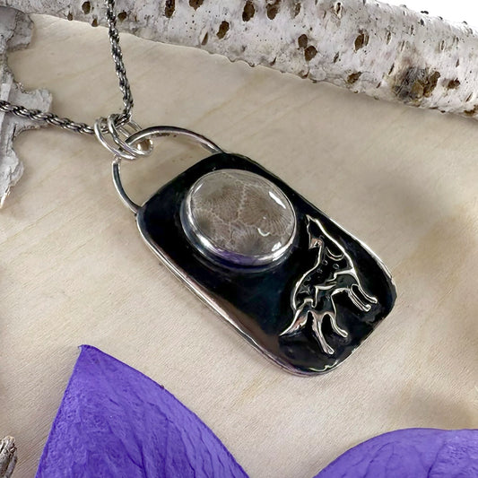 Necklace with a pendant featuring a wolf design on a textured surface