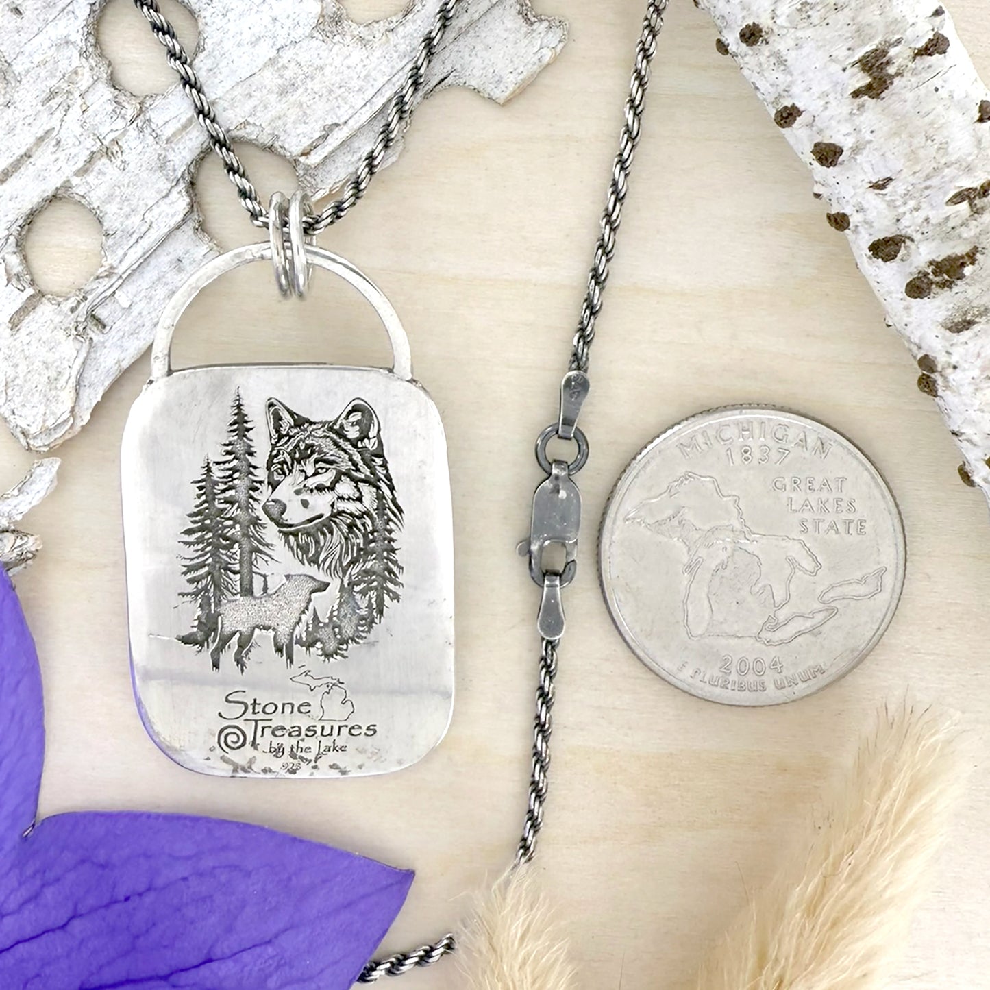 Silver necklace with a wolf engraved pendant on a wood background.