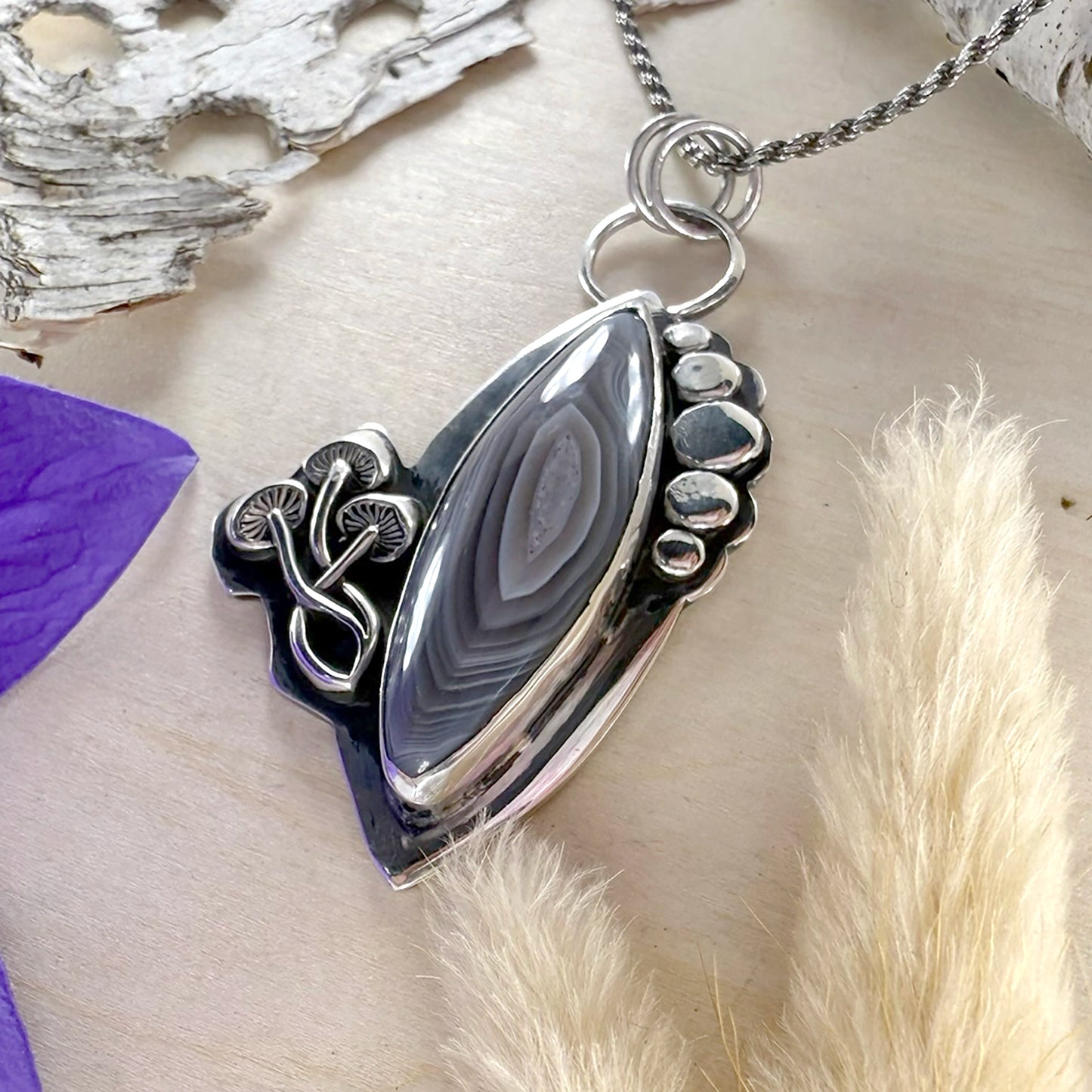 Silver pendant with a central stone on a natural background