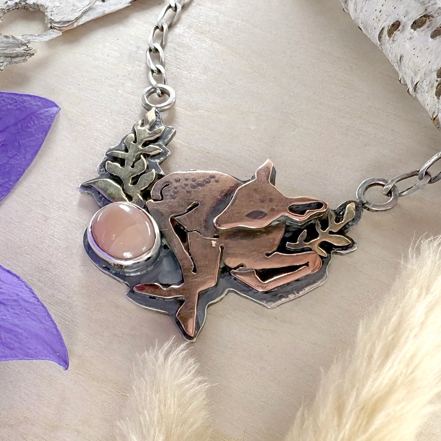 Necklace with a fawn pendant on a textured surface