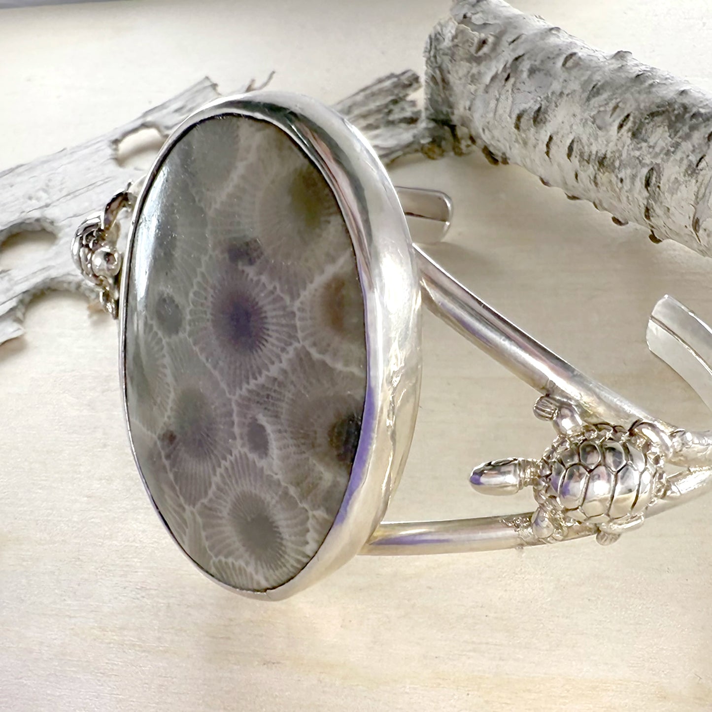 Silver bracelet with a textured stone embellishment on a wood background