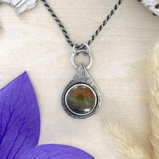 Silver pendant necklace with Lake Michigan Unakite on a wood surface with purple and beige elements