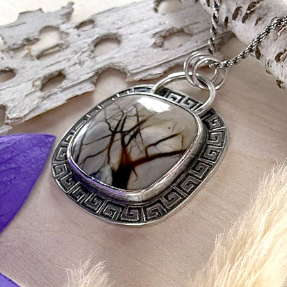 Silver pendant with tree design on a natural background