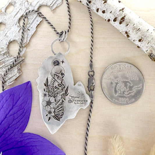 Necklace with a pendant on a wood background, next to a quarter for scale