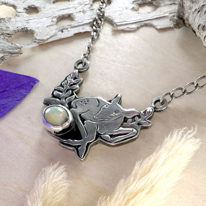 Silver necklace with a pendant featuring a deer and opal on a natural background.