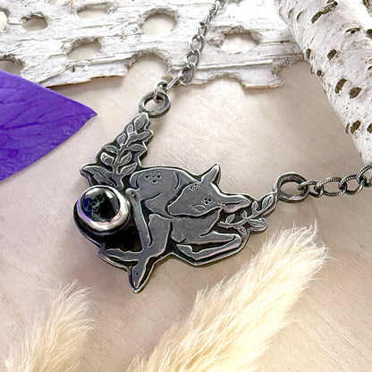 Silver necklace with a deer pendant on a wood surface