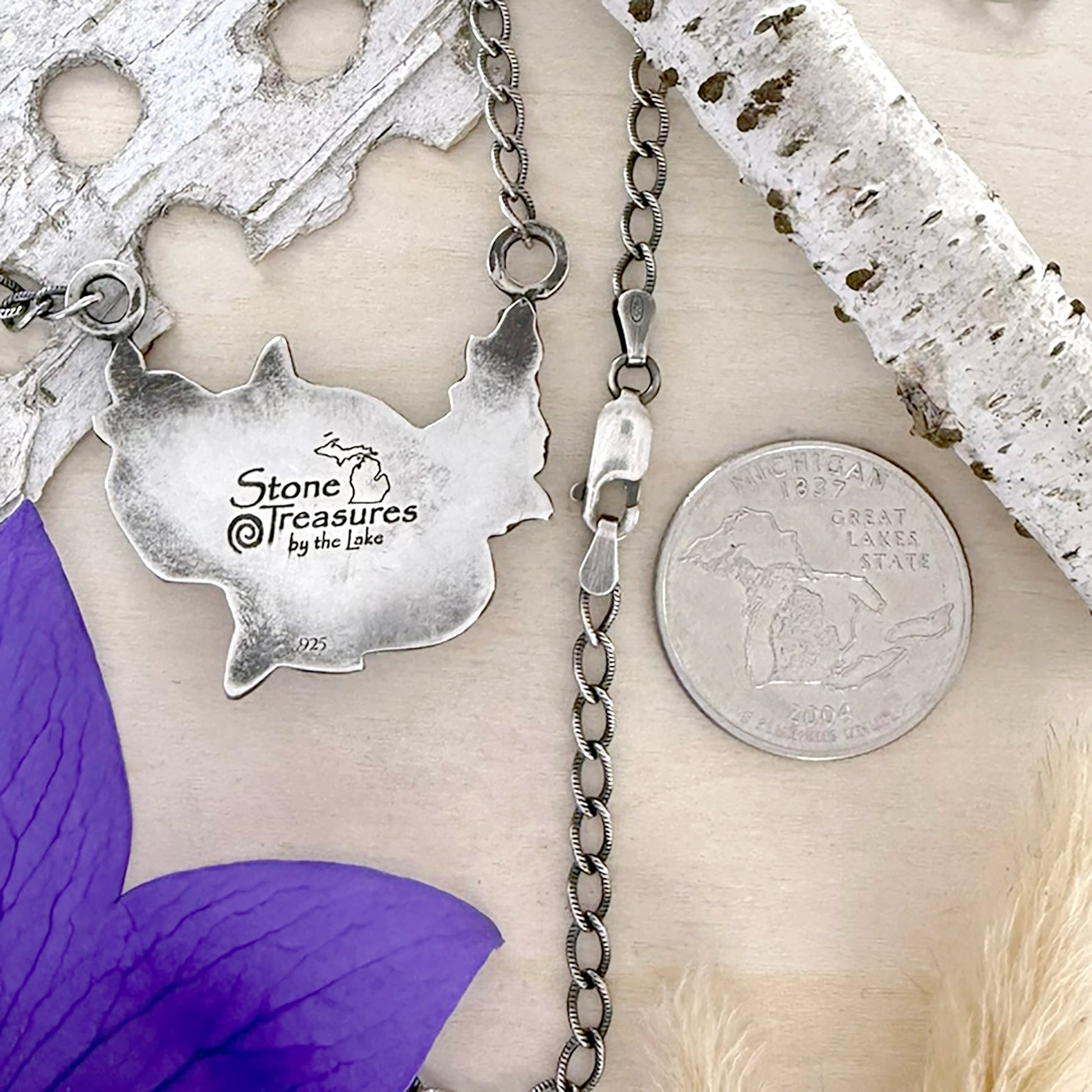 Silver necklace with pendant on a piece of birch bark