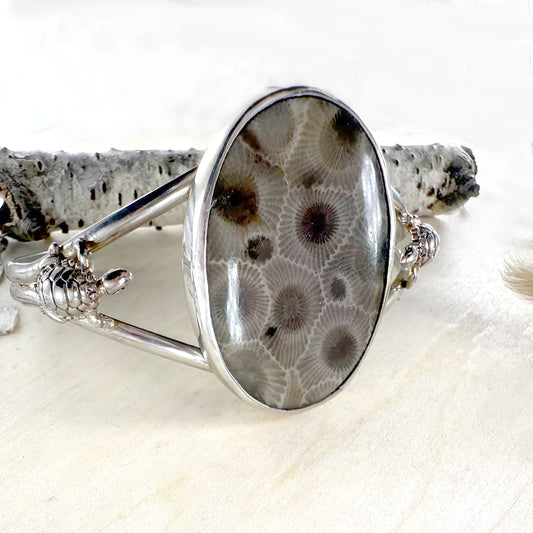 Silver bracelet with a circular design on a white background