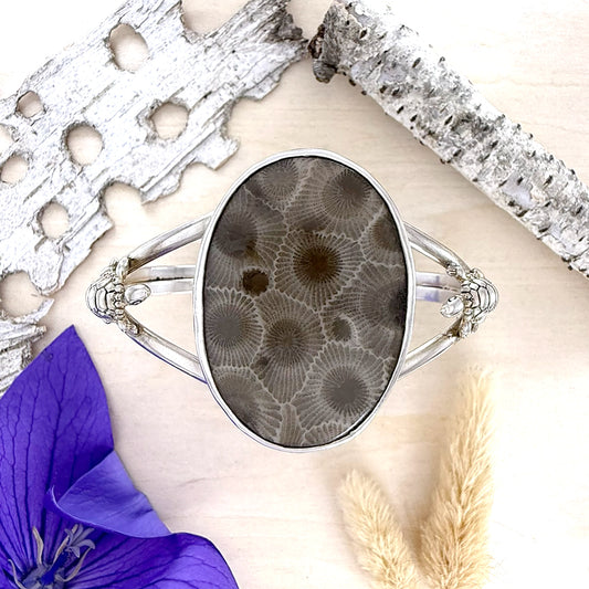 Silver bracelet with a natural stone design on a hand with a purple flower and dried grasses.
