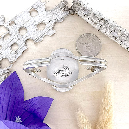 Silver bracelet with 'Stone Treasures by the Lake' engraving  with a purple flower and silver leaf accents.